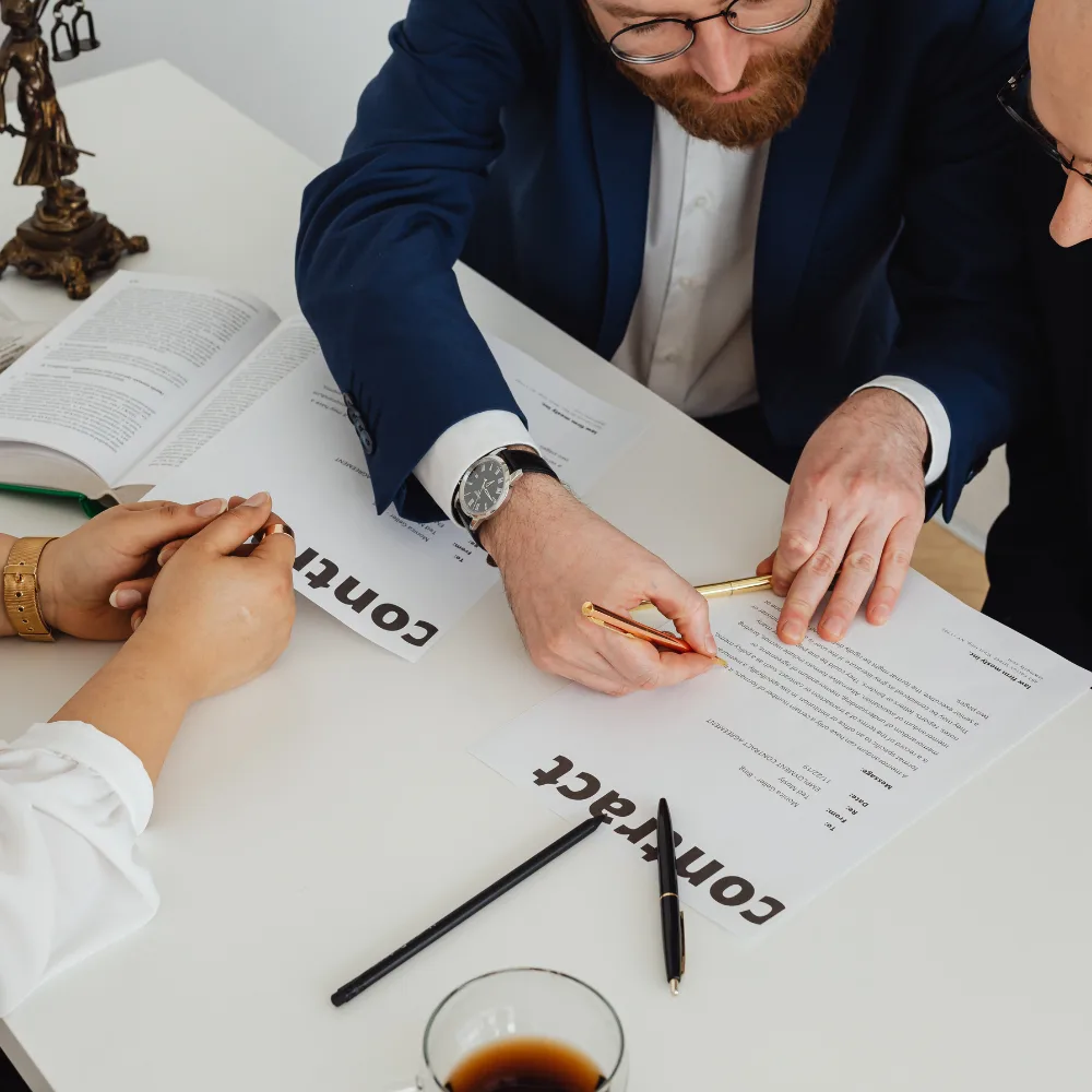 Close-up of hands signing a contract with pens on a glass table