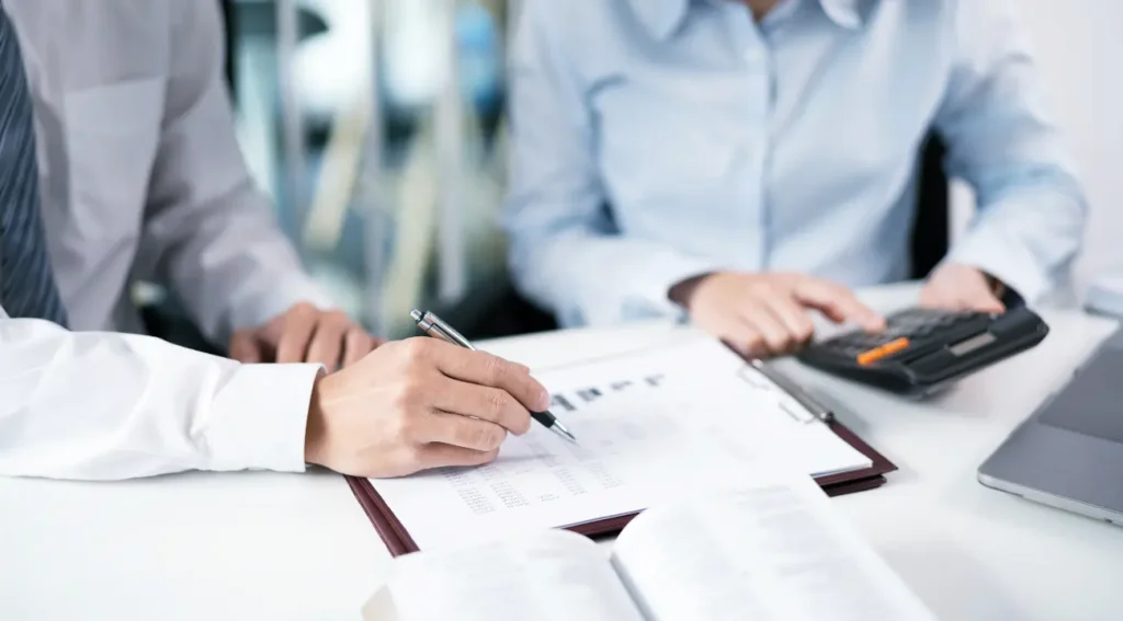 Hands analyzing financial statements and performing due diligence calculations for real estate investments