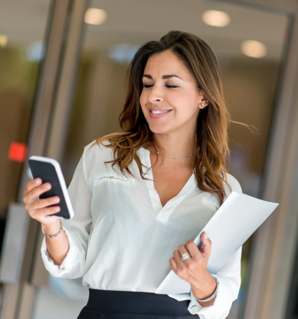 Professional female business owner reviewing documents and checking messages — representing Lions Financial’s ideal client profile