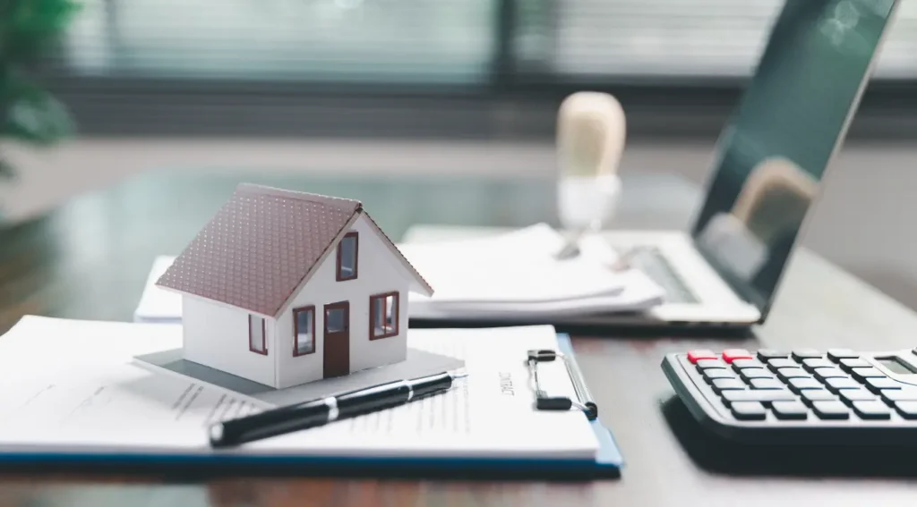 Real estate valuation documents with model house and laptop on desk, representing property analysis and advisory services